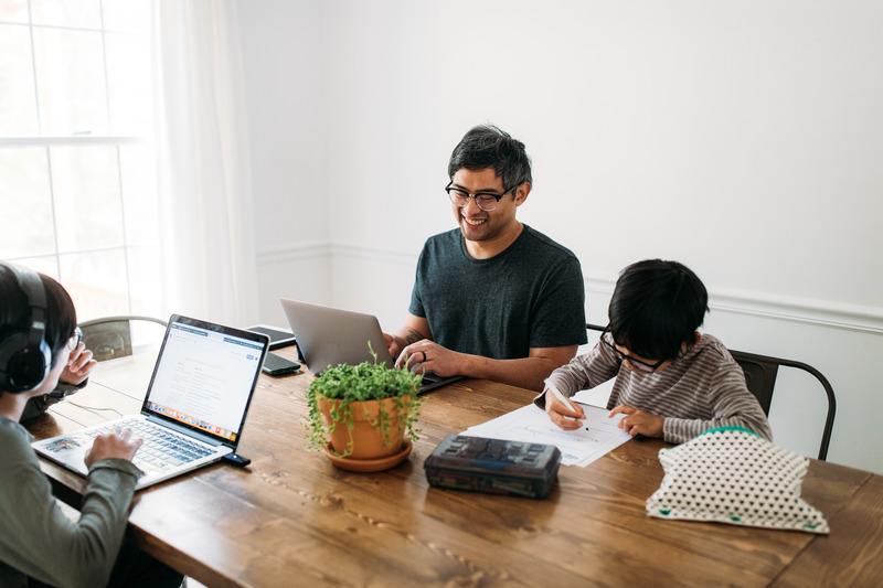 Dad working at table with sons. You can work full time and raise a special needs child.