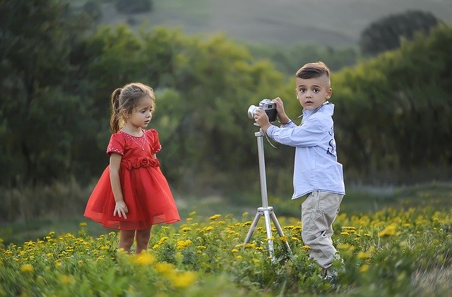 Little boy taking photo of girl. Support siblings of children with autism.