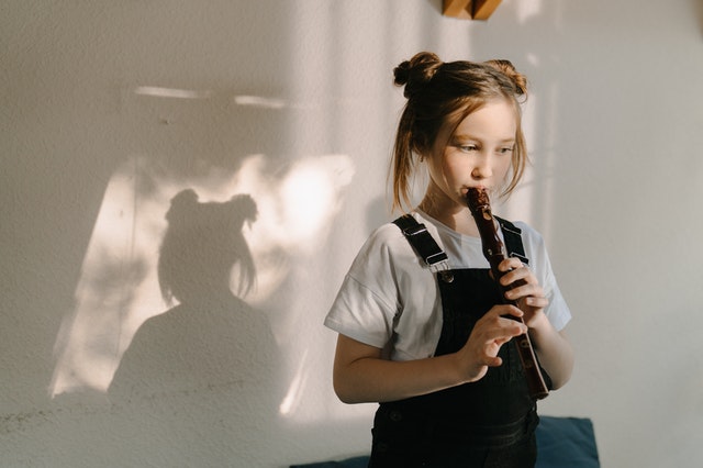 Girl playing a recorder. How music therapy benefits a child with autism.