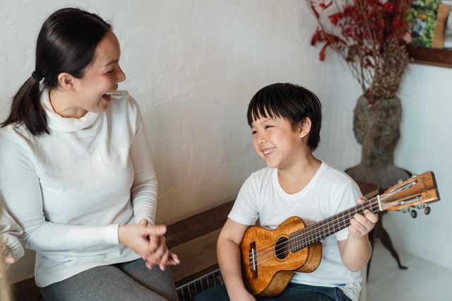 Music therapist with boy playing ukulele. How music therapy benefits a child with autism.