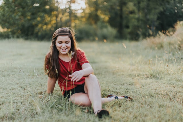 Girl sitting in a meadow. When should you start a transition plan for a teenager with autism?