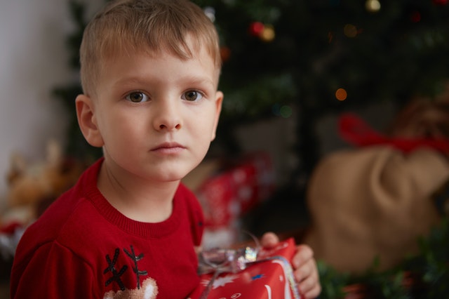 Boy holding a present. Prepare your autistic child for the holidays.