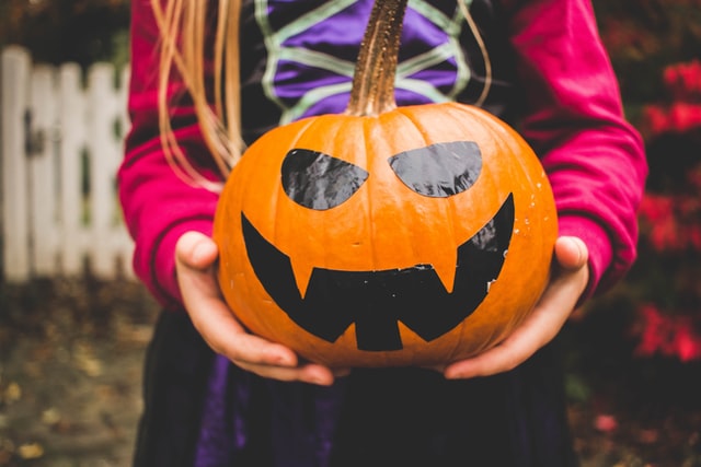 Girl holding pumpkin. Halloween for autism.