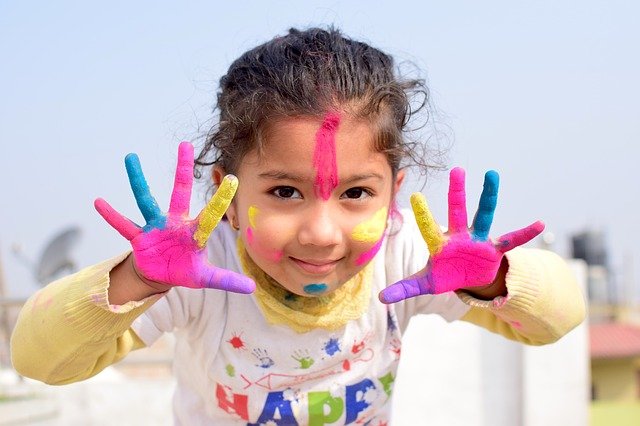 Girl smiling with painted hands. Praising your child is important.