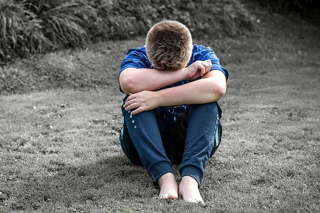 Teenage boy on ground with arms over his head. Help your child through autistic burnout.