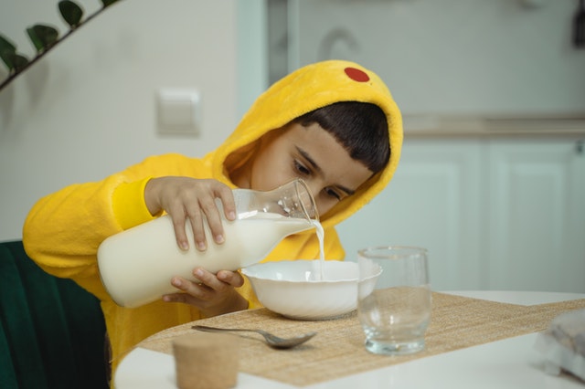 Boy pouring milk in cereal bowl. How can you help your ADHD child combat forgetfullness?
