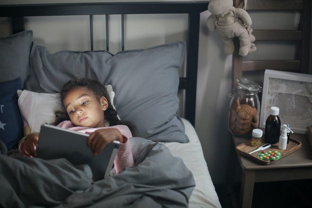Girl reading in bed. Routines are important for children with autism.