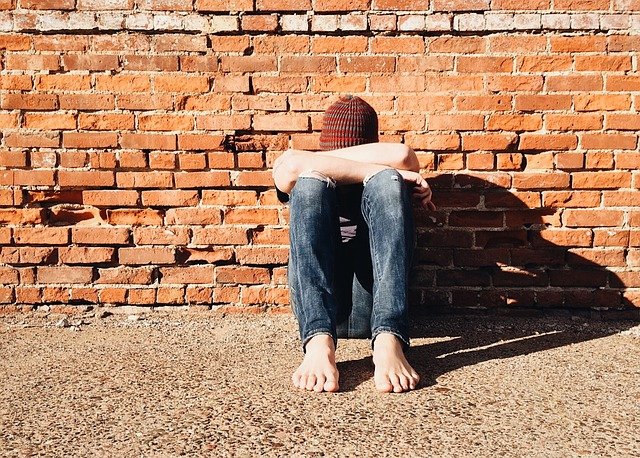 Boy sitting against wall. How can you help prevent bullying of your child with autism?