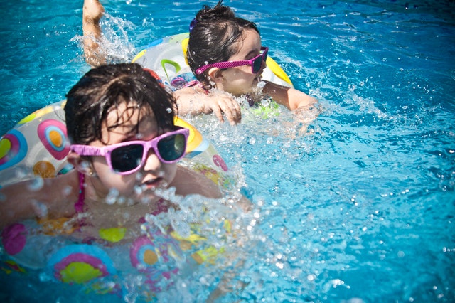 Two girls swimming with sunglasses on.