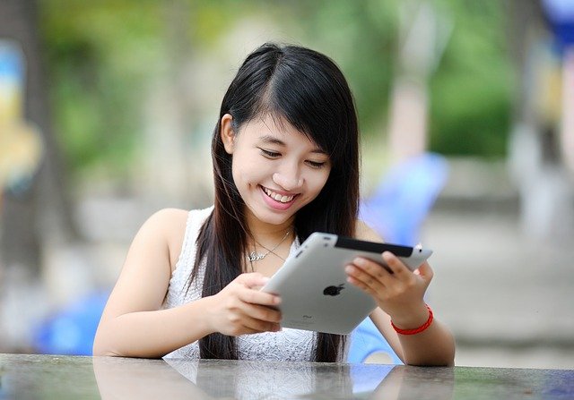 Teen girl looking at iPad. Ensure internety safety for your teen with autism.