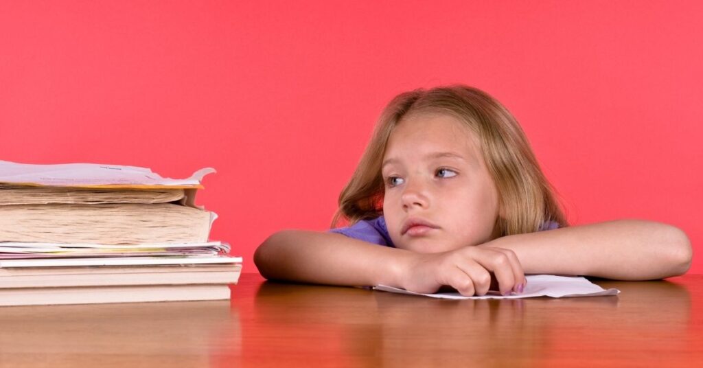 Girl looking at a stack of books with sad face. Teach your child with autism and ADHD executive function skills.
