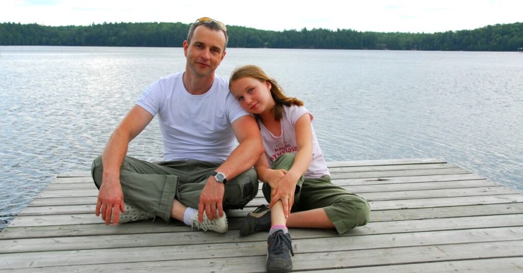 Father and daughter sitting on a dock. Mindfulness can benefit children with autism and their parents.