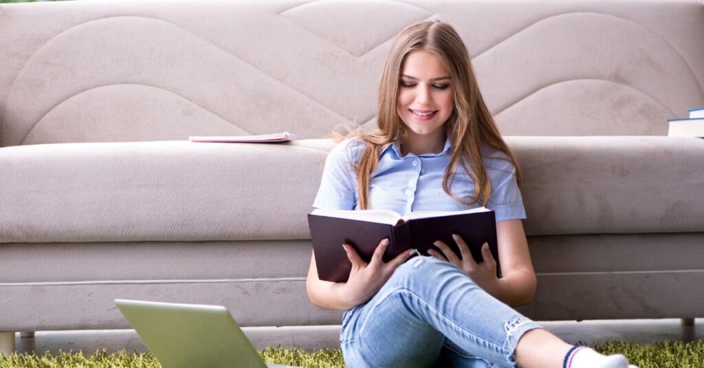Teenage girl sitting on floor reading a book. How to prepare an autistic child for college.