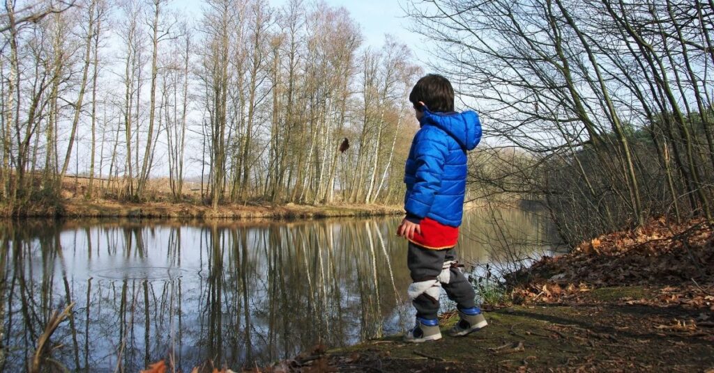 Boy standing by the pond. Help prevent your child with autism from elopement.