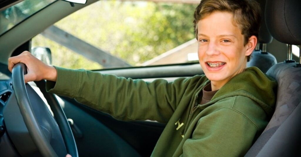 Teenage boy sitting in driver seat of car. It's important to teach life skills to your autistic teenager.