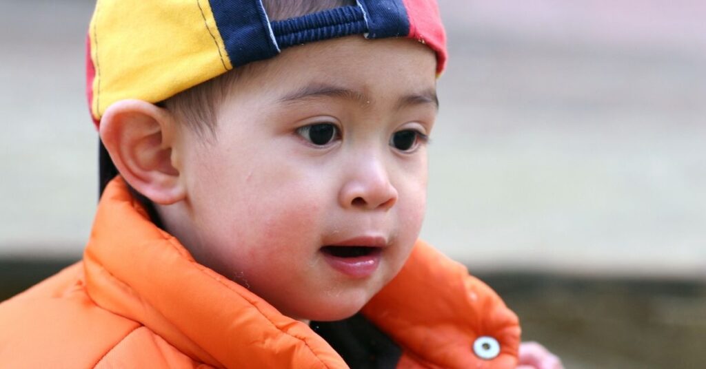 Little boy wearing a baseball cap. Does a speech delay always signal autism in children?