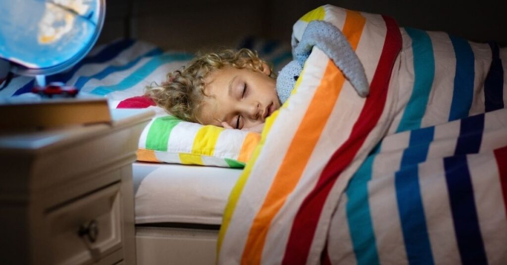 Child sleeping in bed. How to stop bedwetting in children with autism and ADHD.