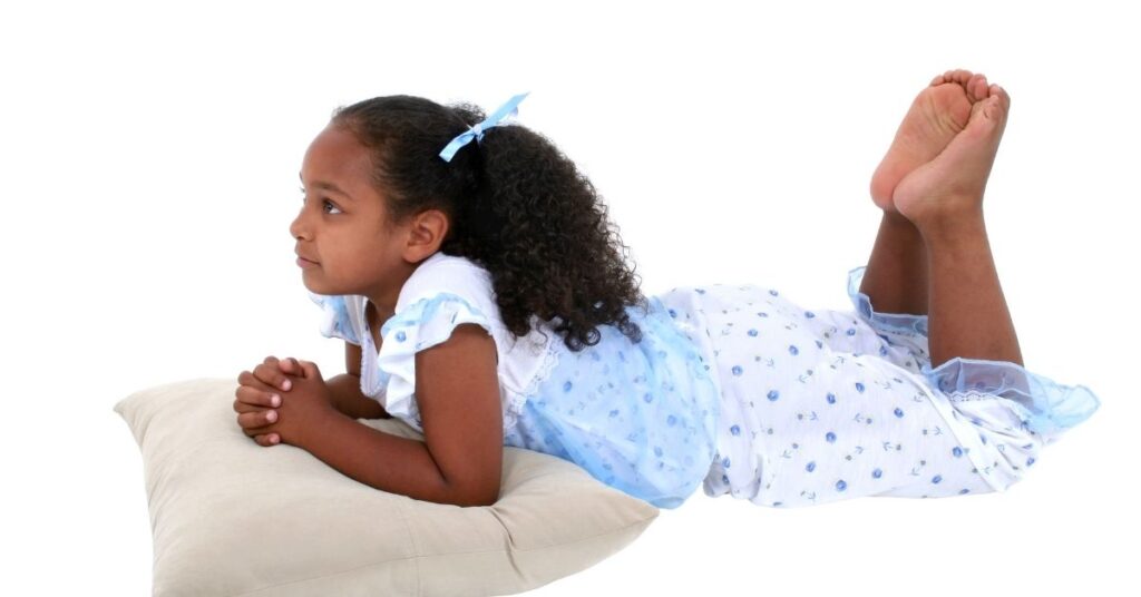 Girl in pajamas laying on her stomach on a pillow. Stopping bedwetting in your child with autism and ADHD.