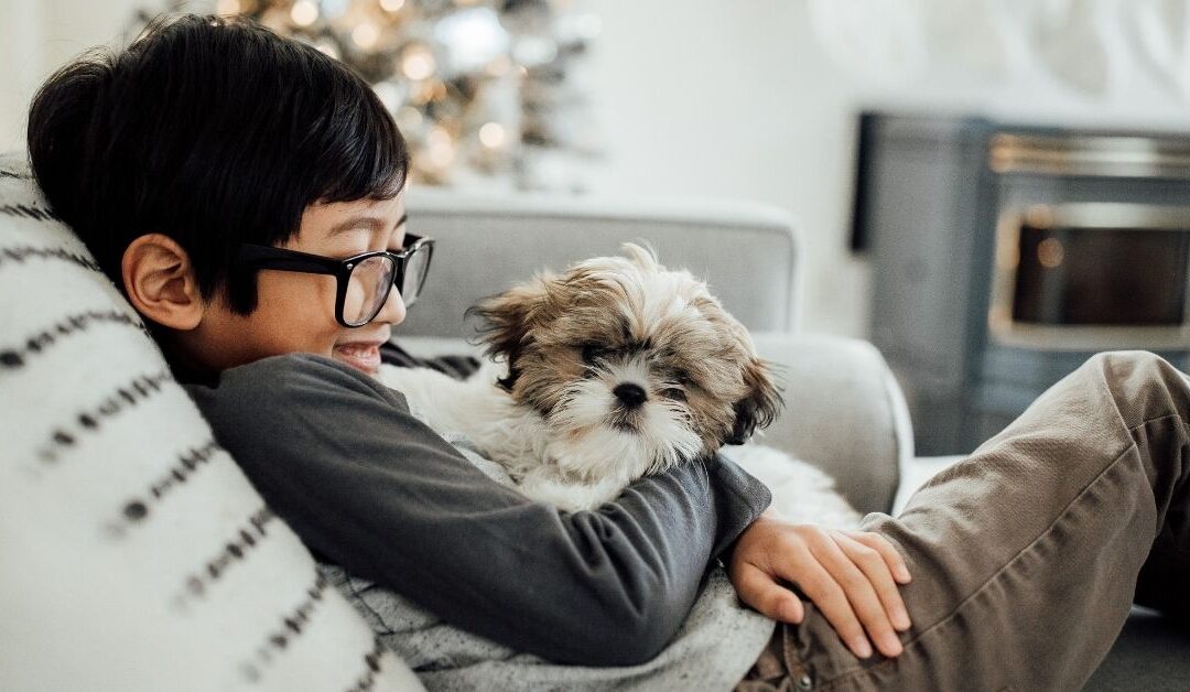 Boy sitting on couch holding his dog.