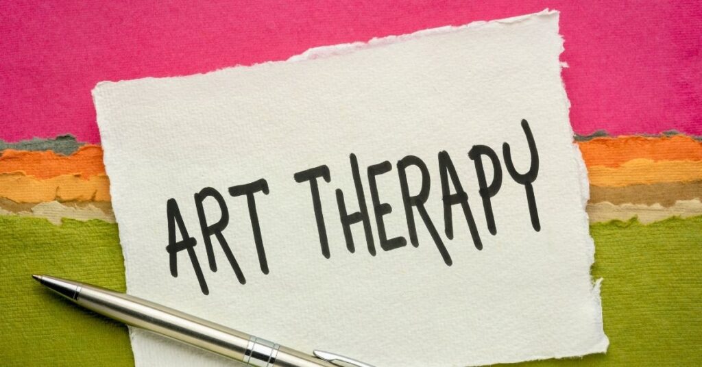 Paper with "Art Therapy" written on it, sitting on a painted multicolor paper. How art therapy can help children with autism and ADHD.