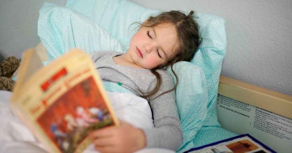 Girl lying in bed and reading a book.