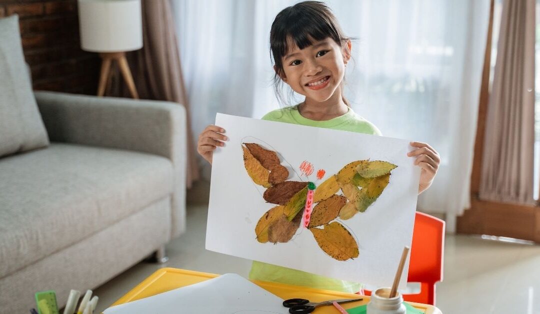 Little girl holding butterfly art work.