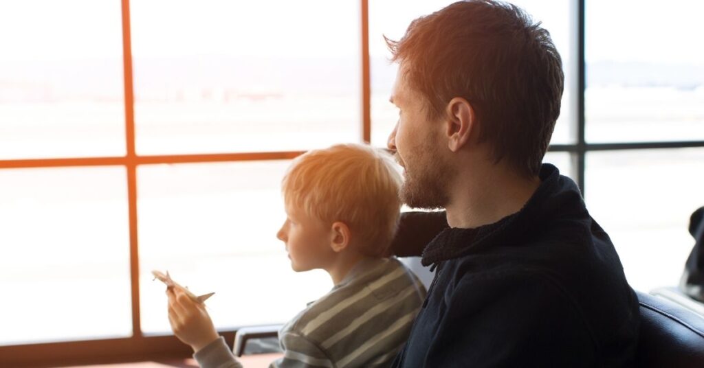 Dad holding boy on lap at the airport. How to prepare your child with autism and ADHD for an airplane flight.