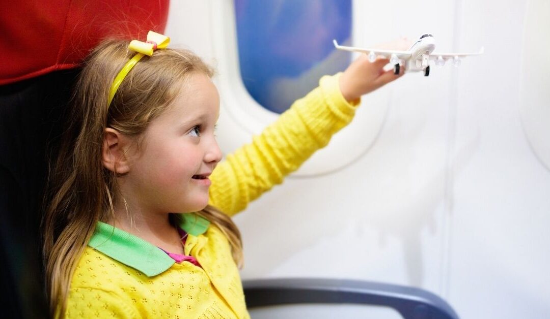 Little girl sitting on an airplane holding a toy airplane in her hand