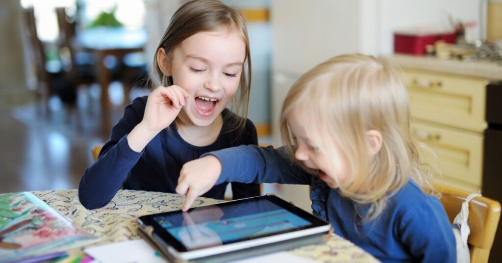 Two little girls playing on an iPad.