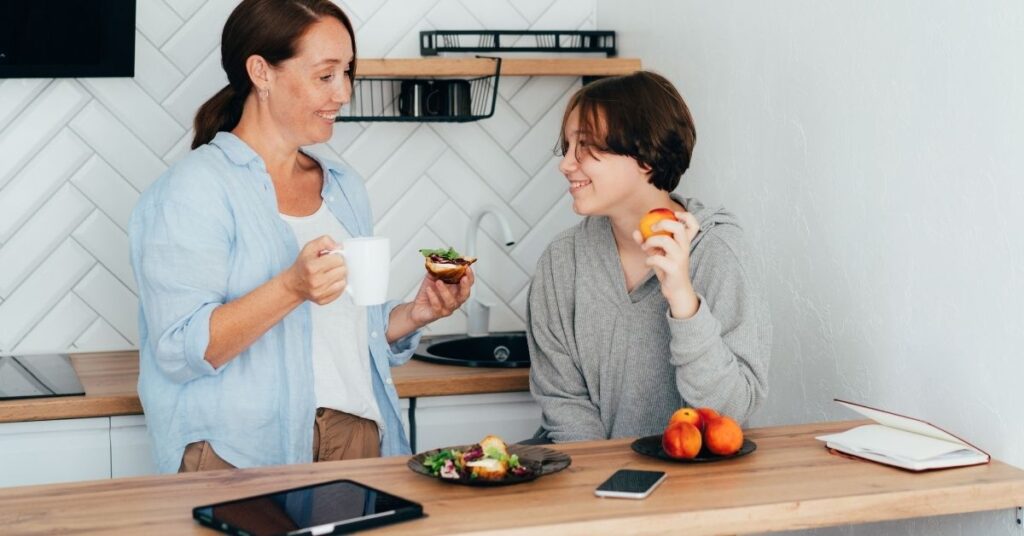 Mom talking with teen at kitchen counter. How can you talk to your autistic teen about the transition after high school?