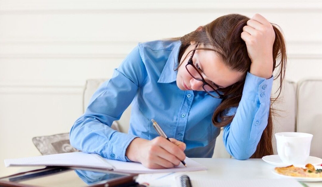 Teen girl sitting at a desk and leaning her head into her hand as she studies