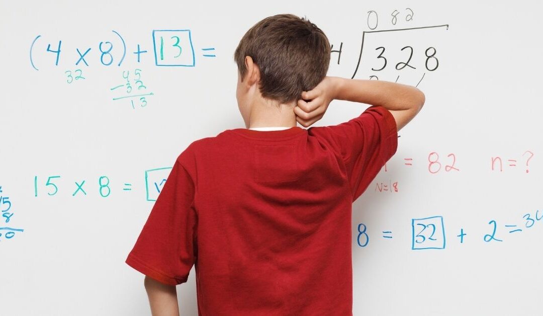 Boy facing a whiteboard with a math problem written on it.