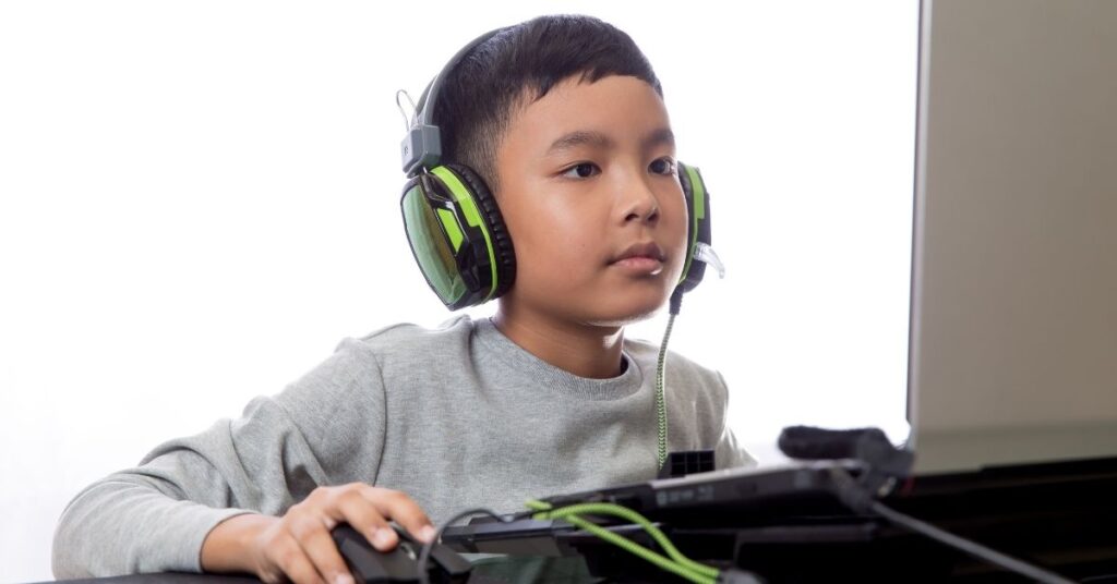 Boy wearing headphones and playing a game on the computer