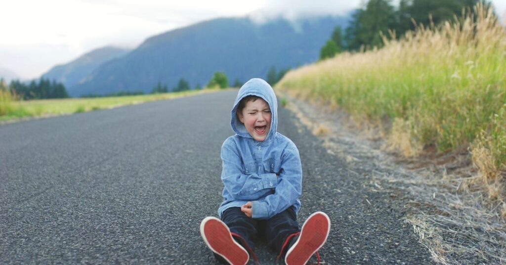 Boy sitting in road crying. How can you make transitions easier for your autistic child?