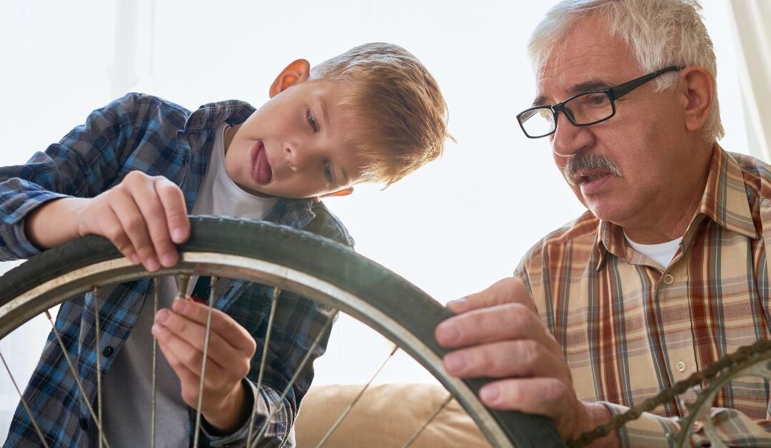 Grandfather teaching boy to fix a bike.