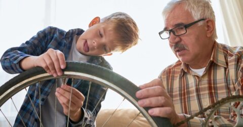 Grandfather teaching boy to fix a bike.