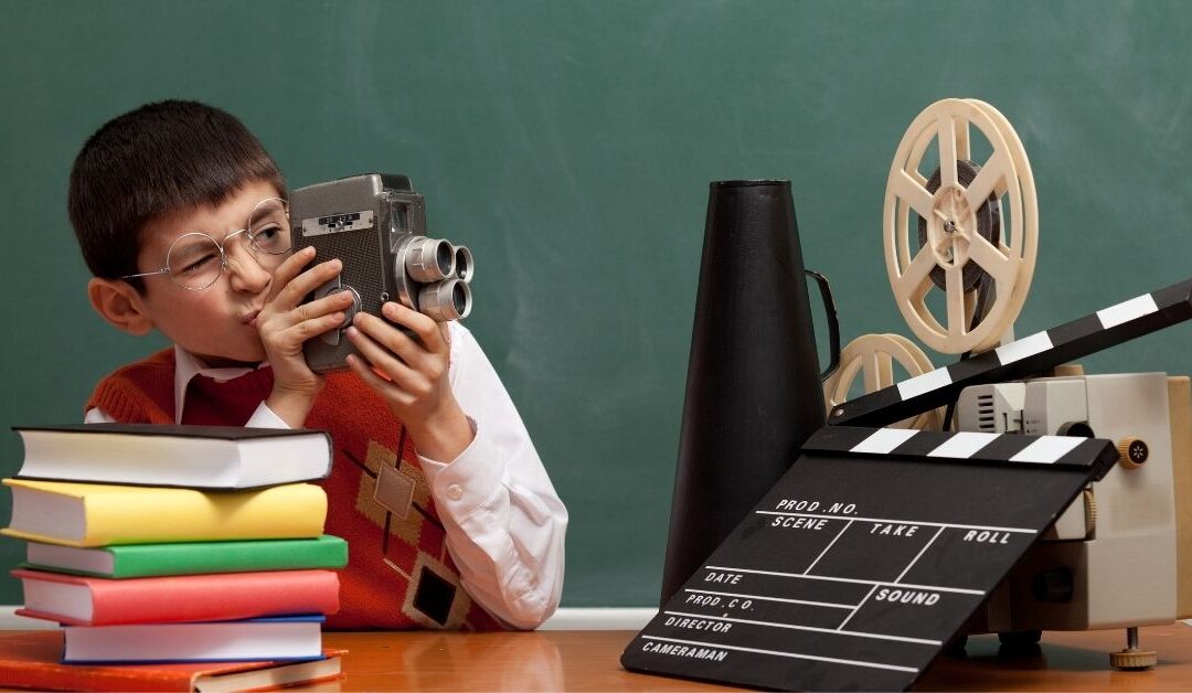 Boy looking through a camera with movie making equipment around him