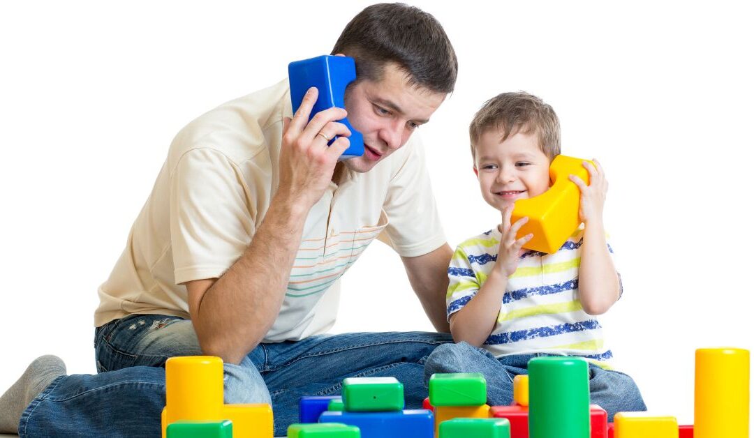 Dad and son playing with blocks and acting like they are talking on the phone to each other