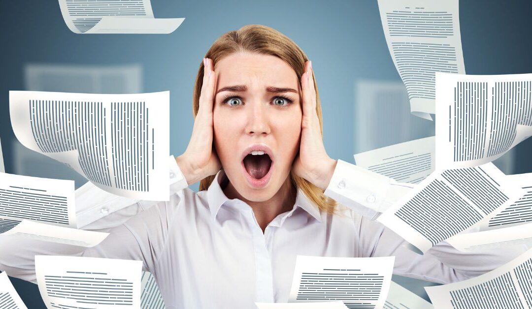 Woman with overwhelmed look on face with papers flying around her