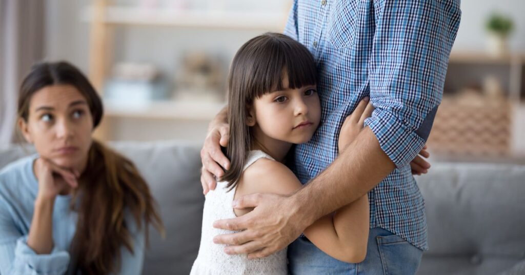 Girl clinging to her dad. How can you help your child with autism overcome school avoidance?