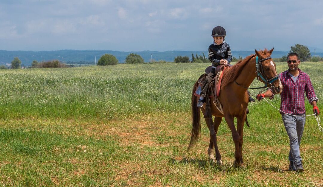 Autistic boy riding horse with equine therapist walking along