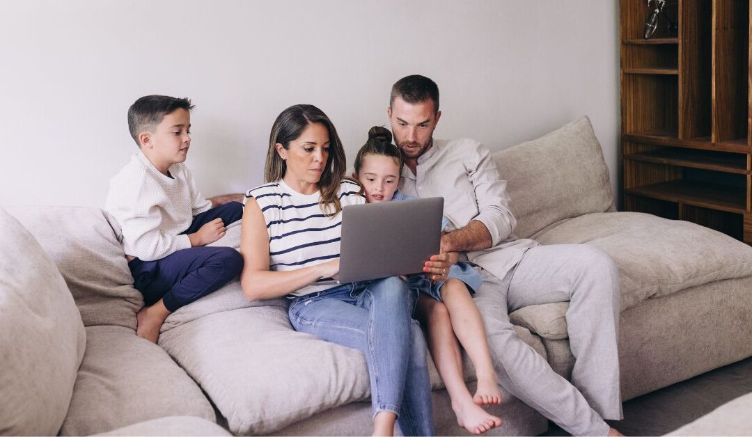 Family sitting on couch looking at computer
