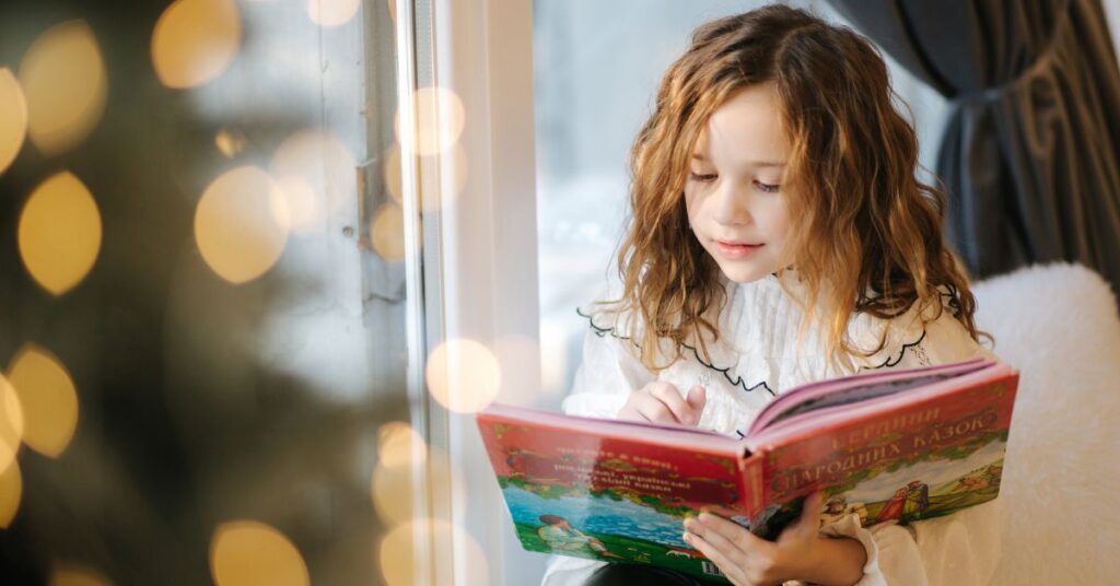 Girl reading a book in front of window. How do you prepare relatives for holidays with your autistic child?