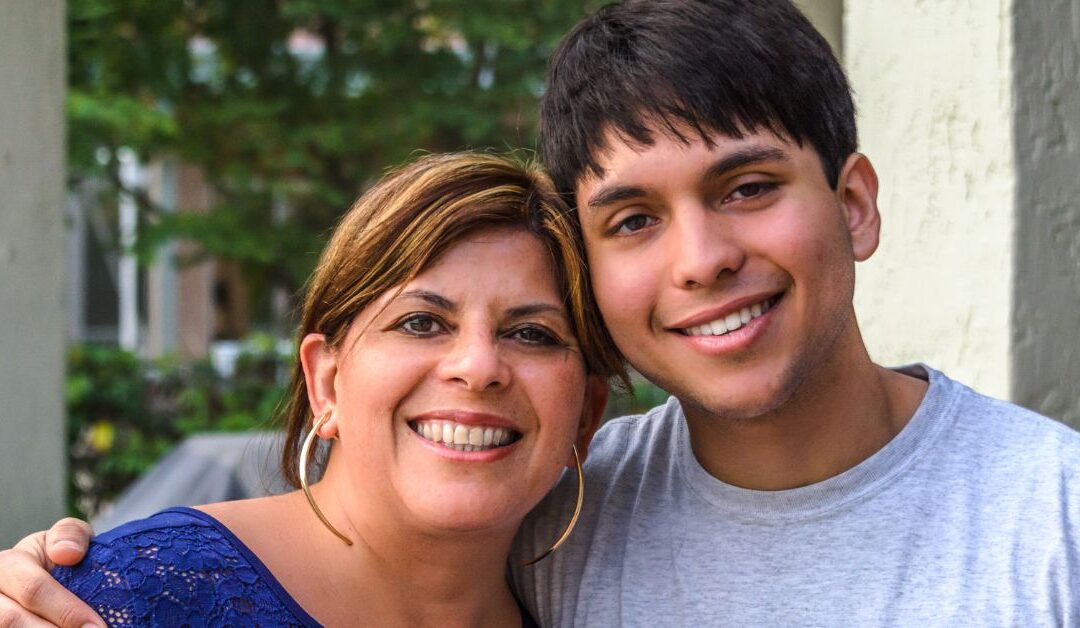 Mom standing with her young adult son.