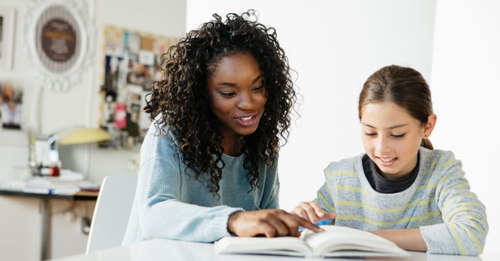 Tutor working with a girl and looking at a book. How do you determine if a tutor can help your autistic child.