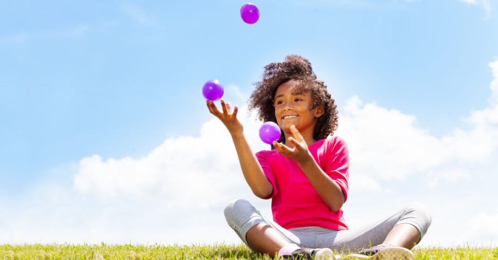 Girl sitting outside juggling balls. Look at the positive side of autism and ADHD behaviors.