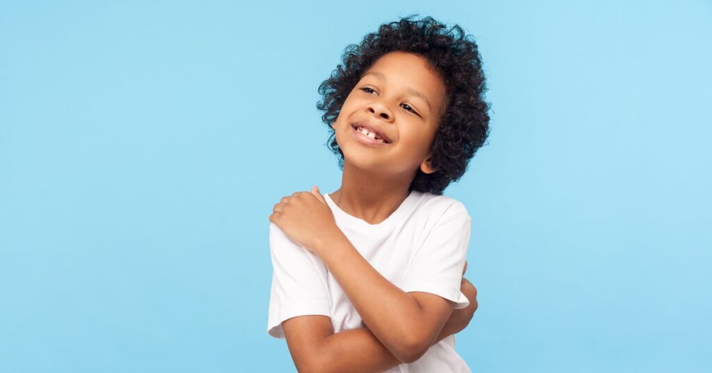 Boy hugging himself.