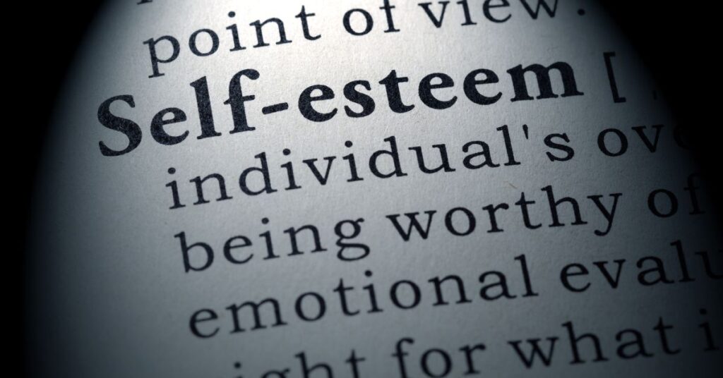 Self-esteem typed on a paper with the definition. How can you help your child with autism and ADHD improve their self-esteem?