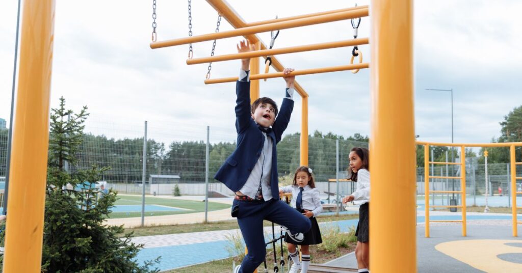 Boy hanging off of playset while two girls watch him. How can you encourage your child with autism and ADHD to try new activities?