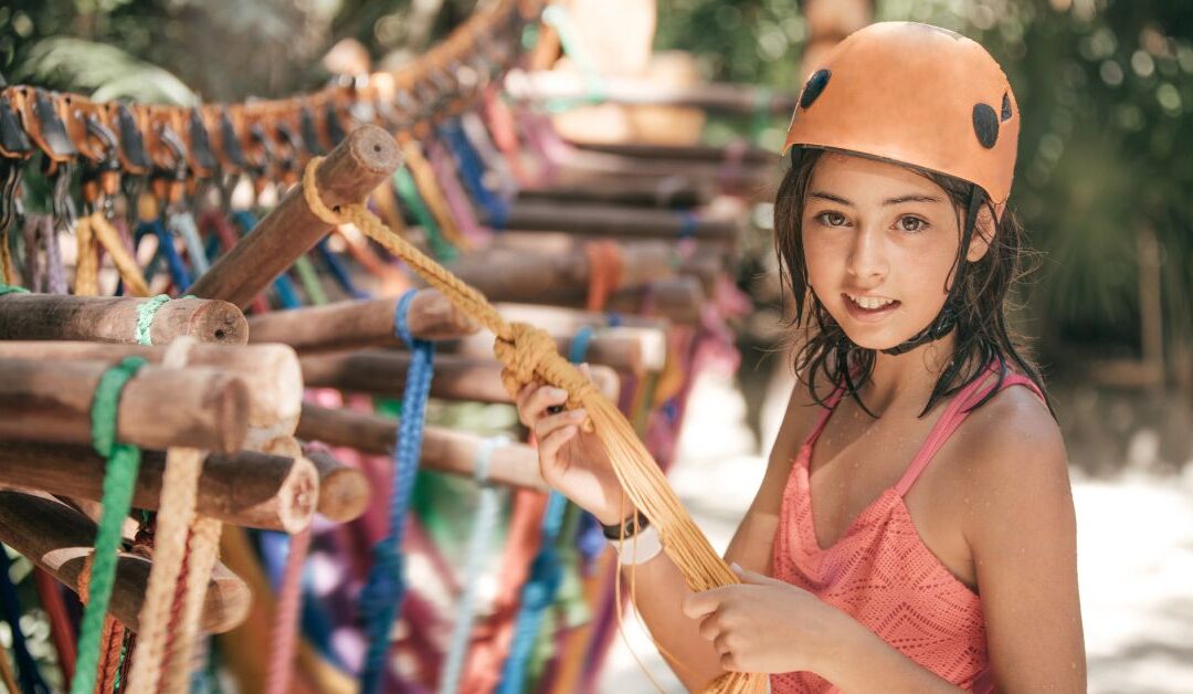 Girl in helmet holding multi colored ties on a branch.
